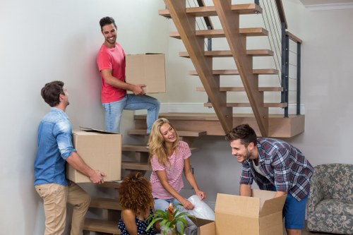 Professional movers carrying household furniture through a Borough property